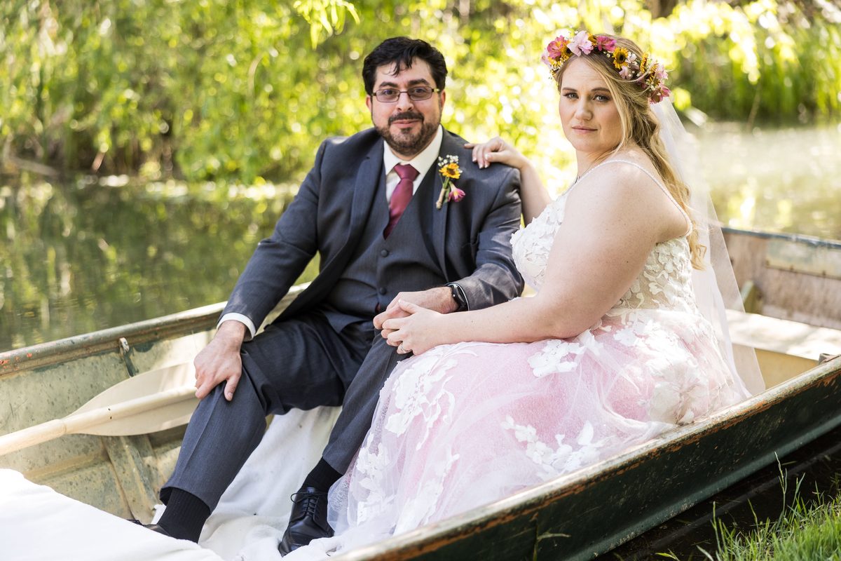 Abney and Chris sit together in an old rowboat at the edge of the pond