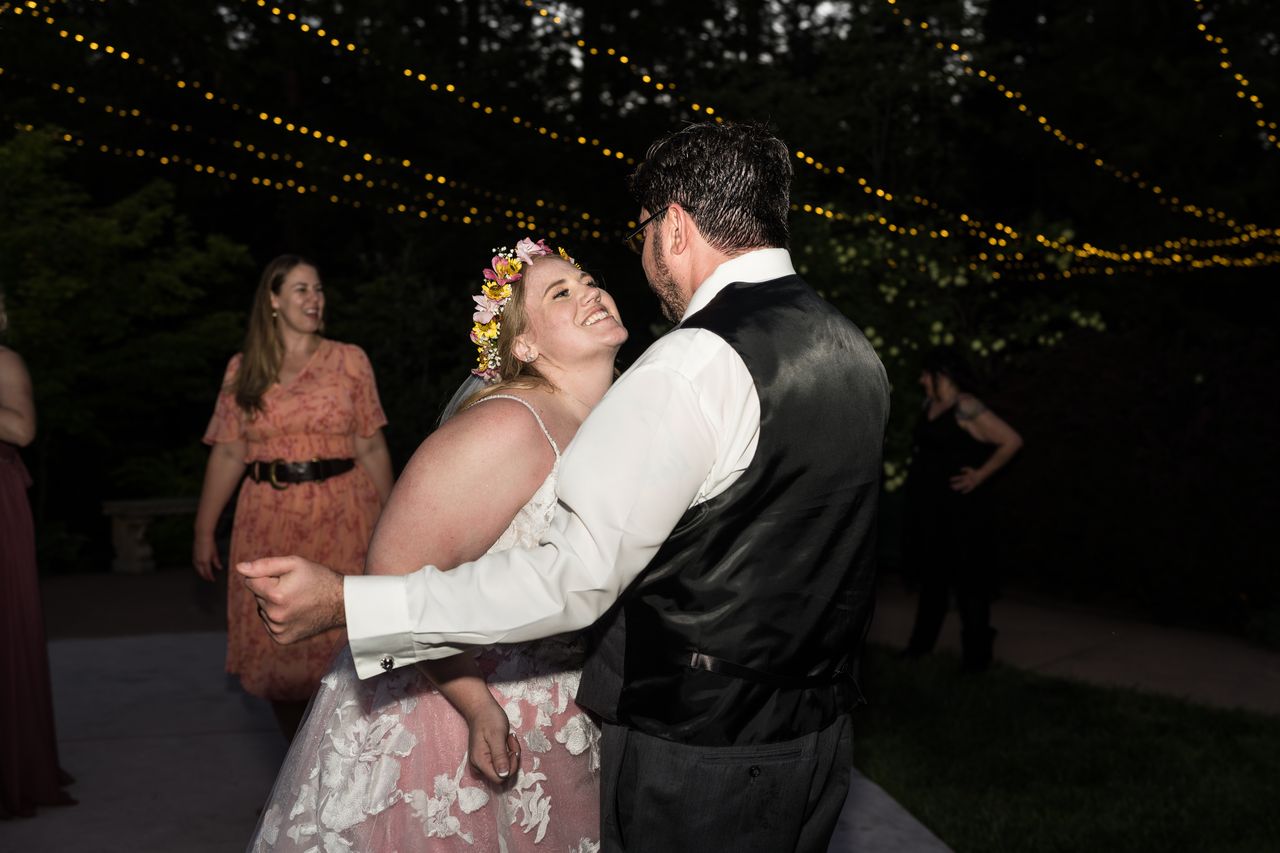 Abney beams up at Chris as they dance together under the string lights at night