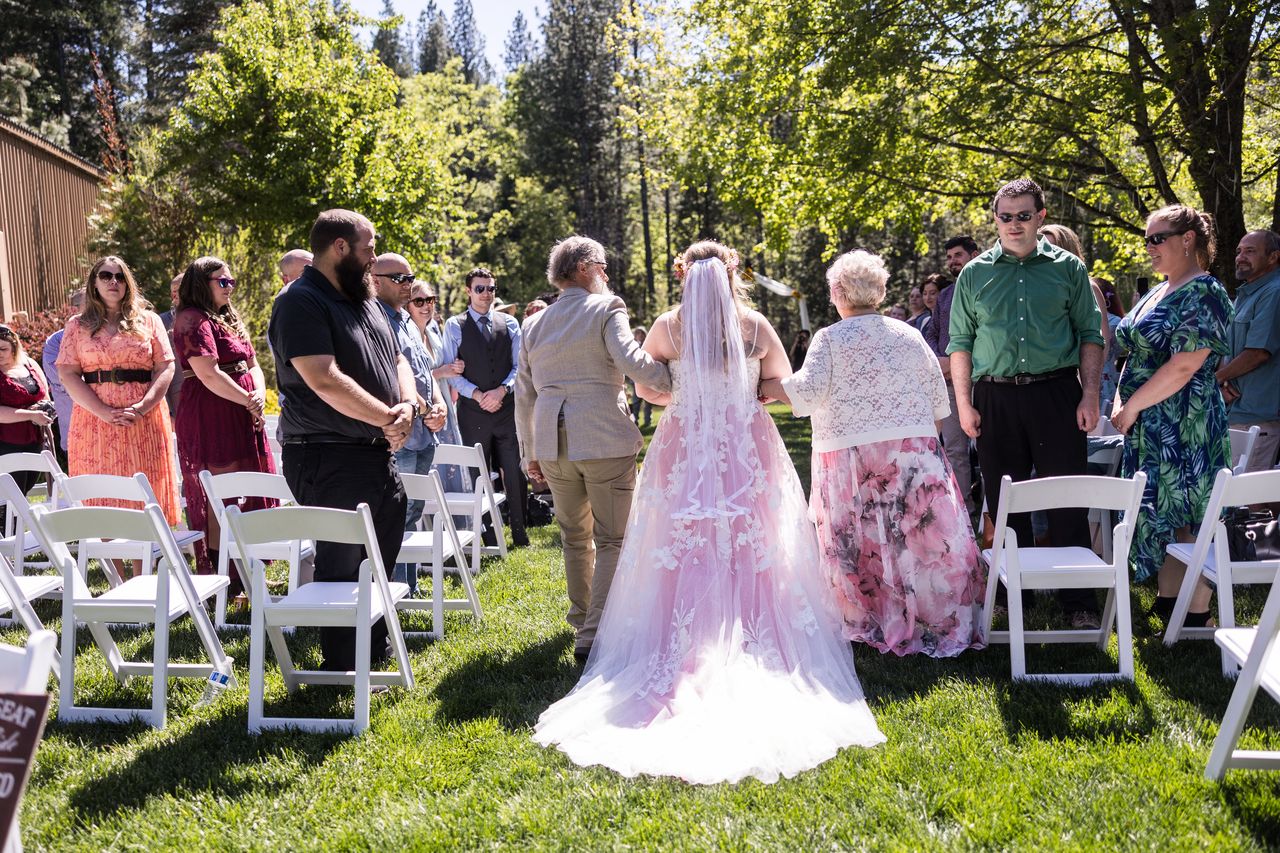 Abney walks down the aisle, seen from behind, as her guests stand