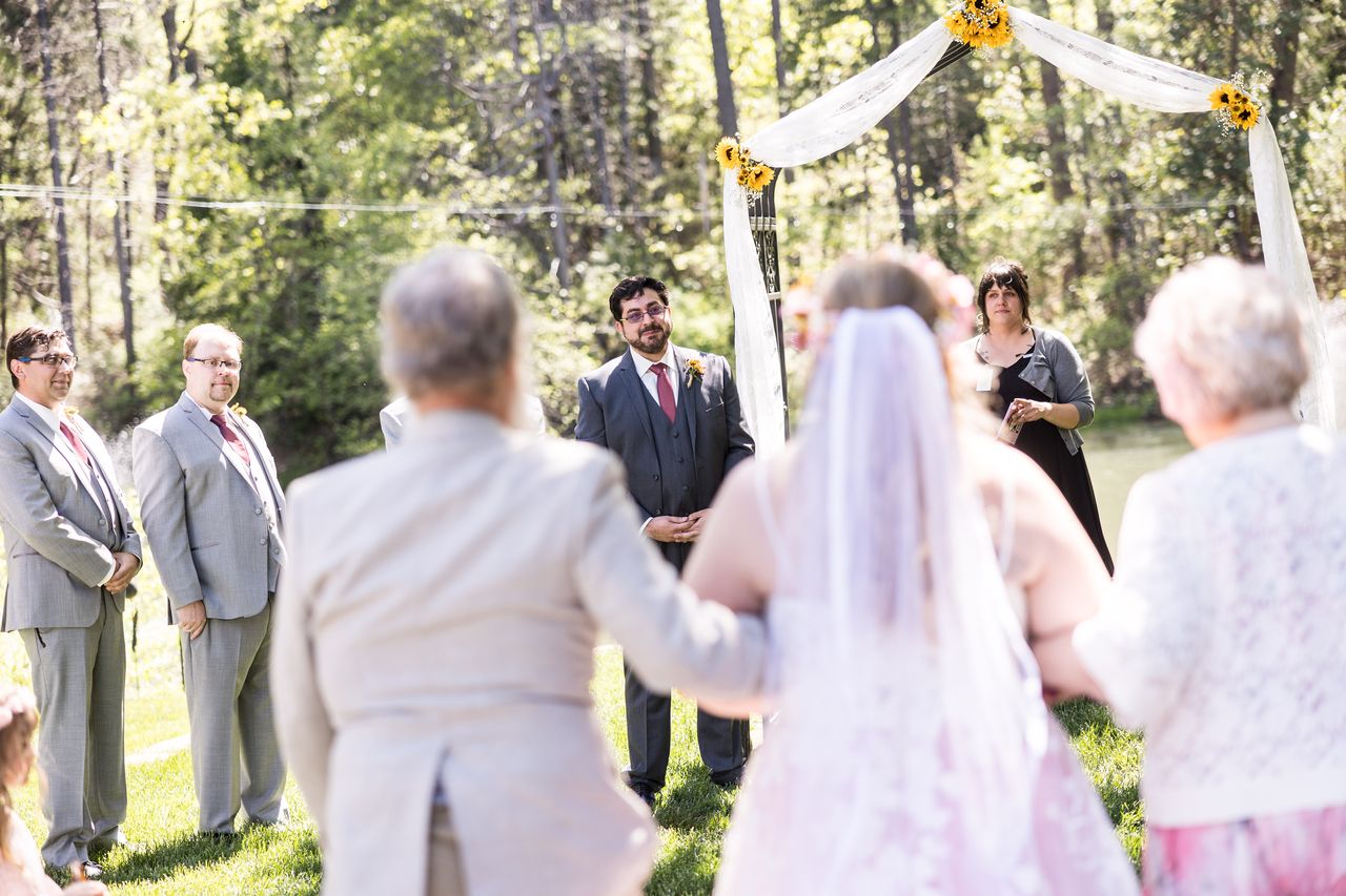 Abney approaches the arbor on the arms of two family members while Chris waits