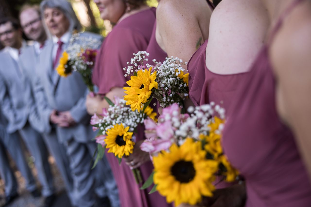 A bridesmaid's bouquet of sunflowers in sharp focus, with the wedding party blurred behind it