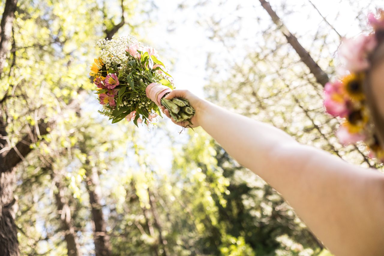 Abney holds her bouquet out at arm's length toward the trees