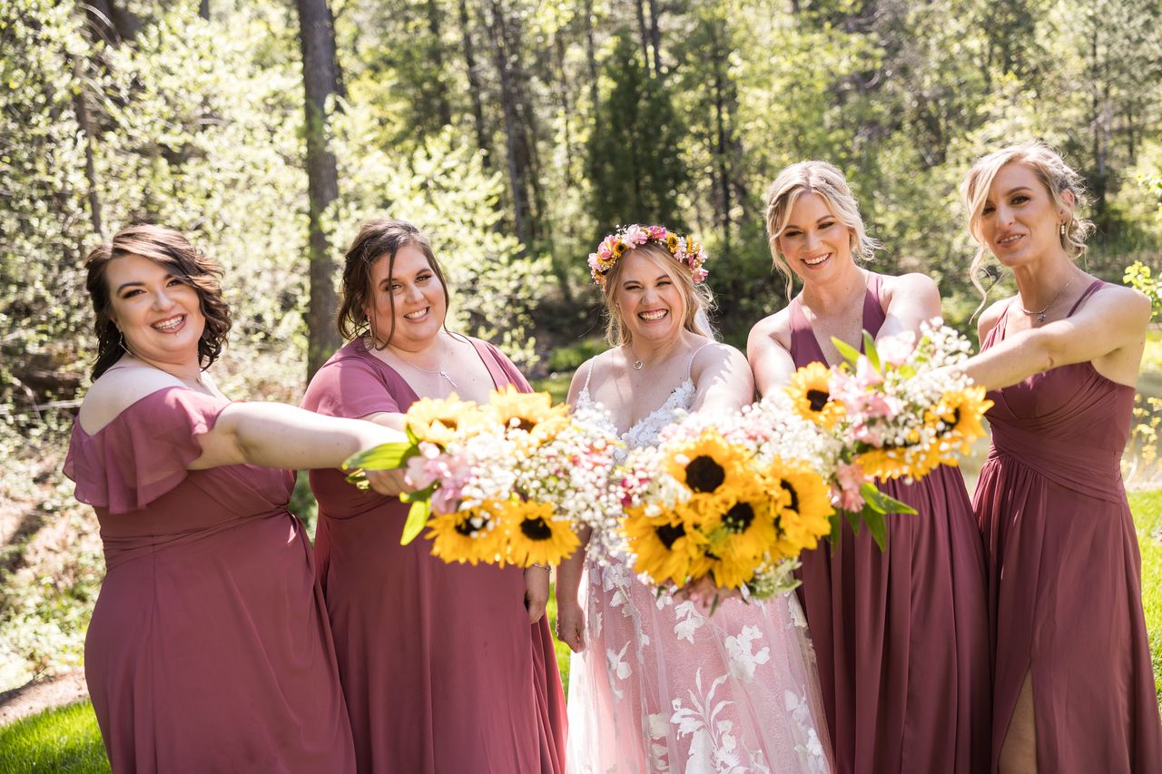Abney and her four bridesmaids hold their sunflower bouquets out toward the camera