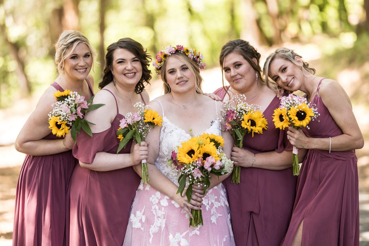 Abney and her bridesmaids lean in close, holding their sunflower bouquets