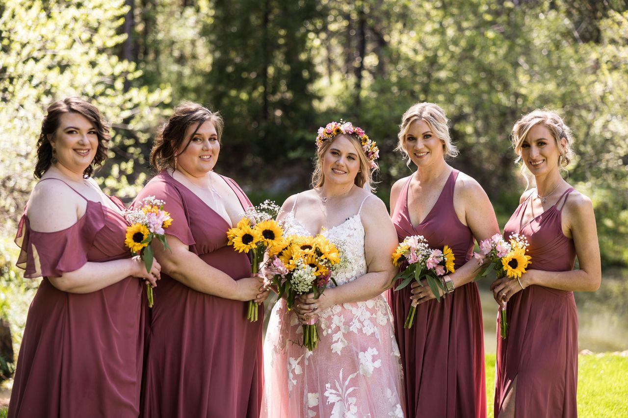 Abney stands with her four bridesmaids in mauve dresses, each holding a sunflower bouquet