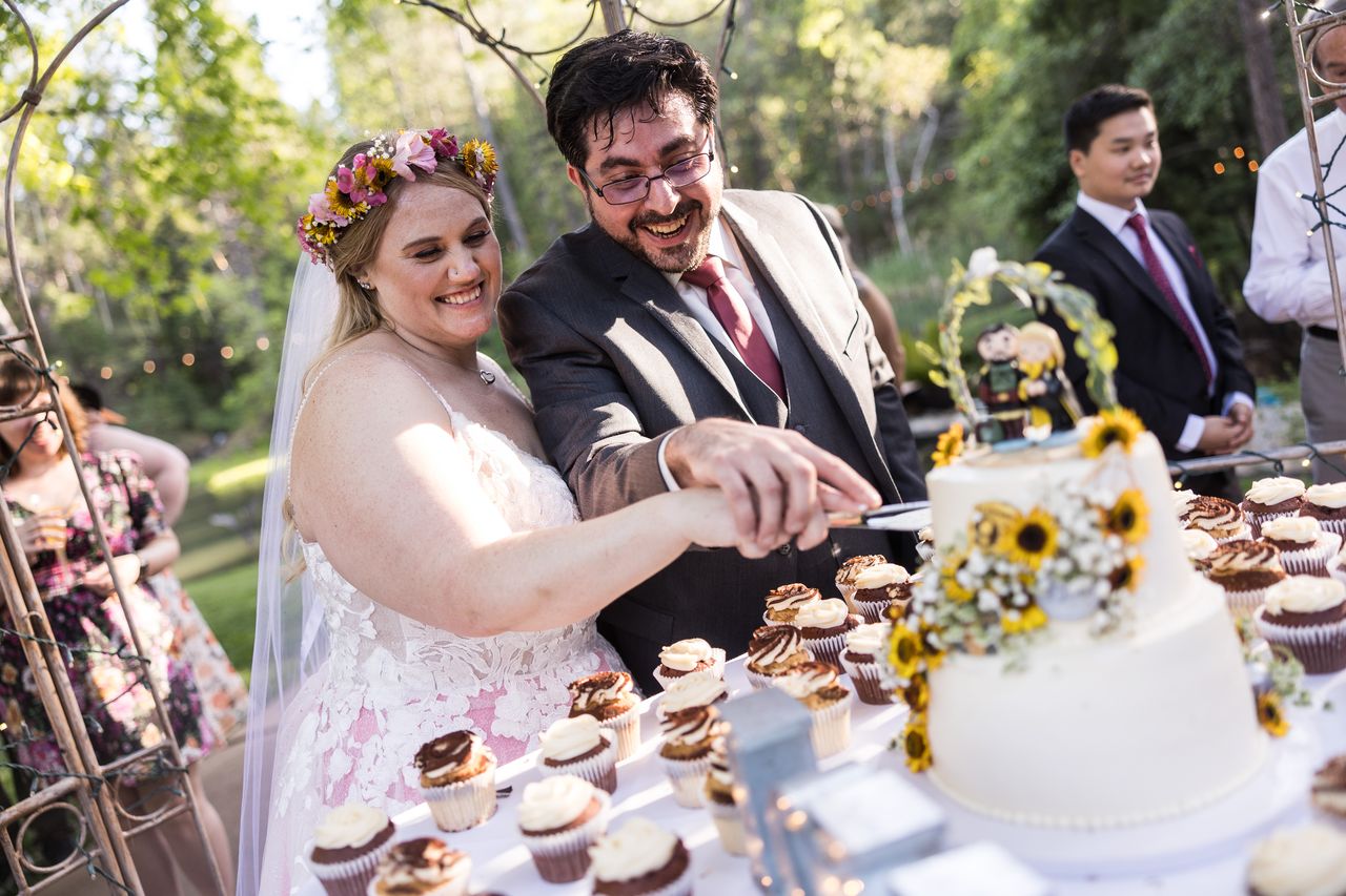 Abney and Chris smile as they cut their sunflower wedding cake together