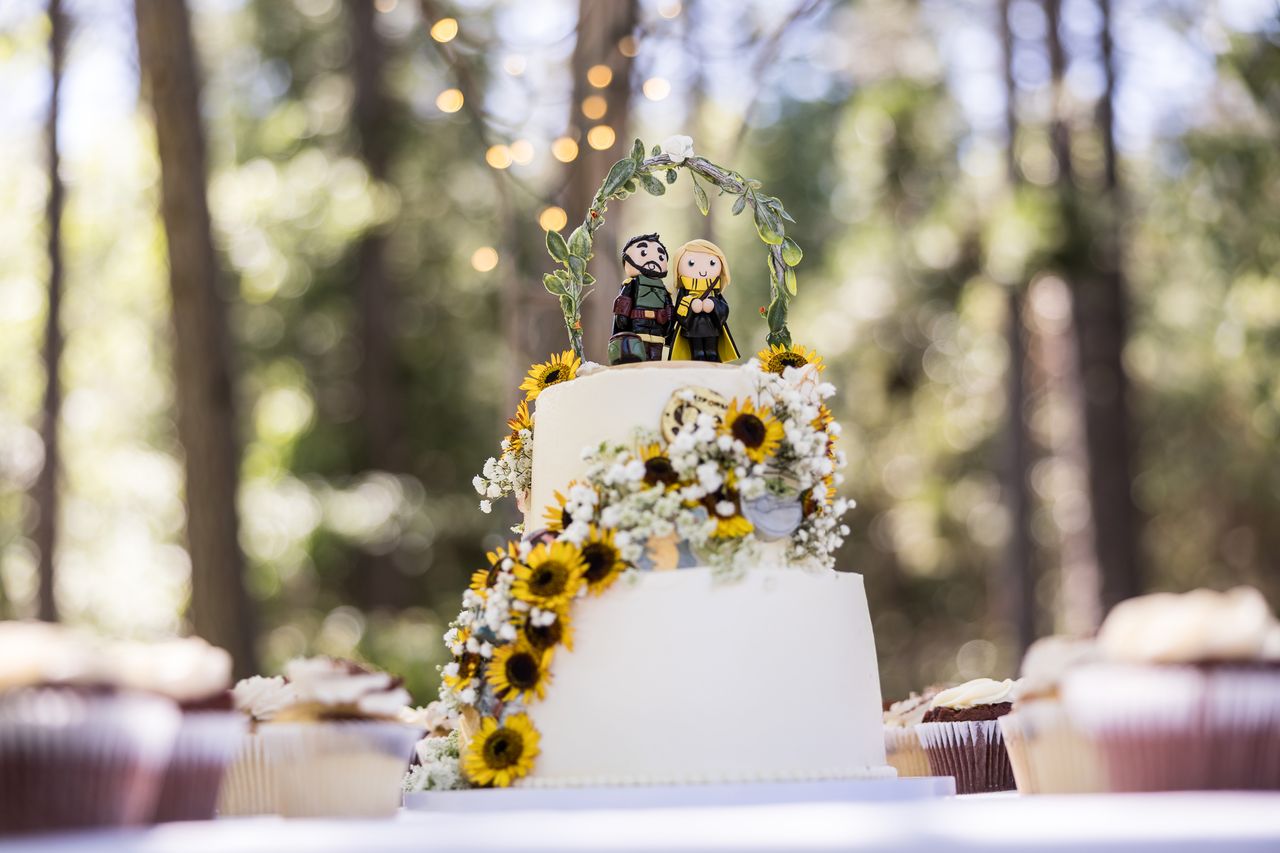 The two tier wedding cake wrapped in sunflowers, with figures of the couple on top