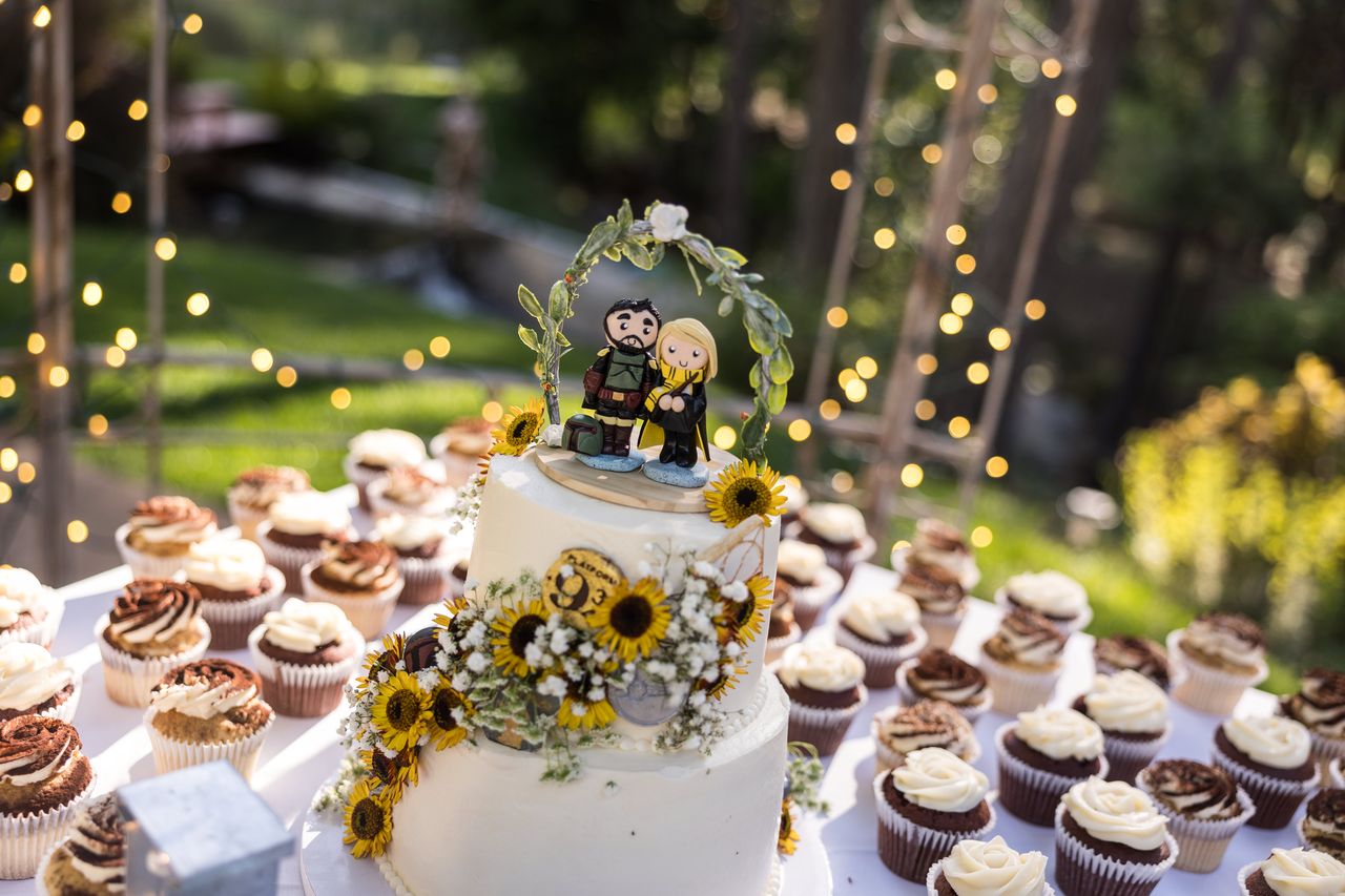 The wedding cake with its figures of the couple on top, string lights glowing behind it