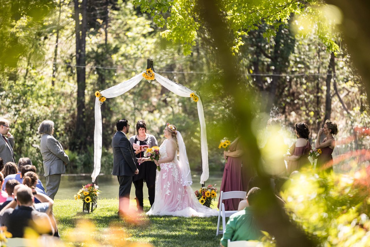 Abney and Chris at the arbor, framed by bright green leaves