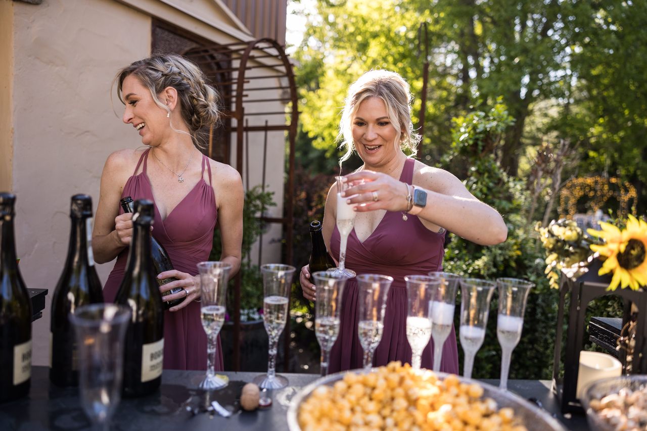 Two bridesmaids pour champagne into glasses for the toast