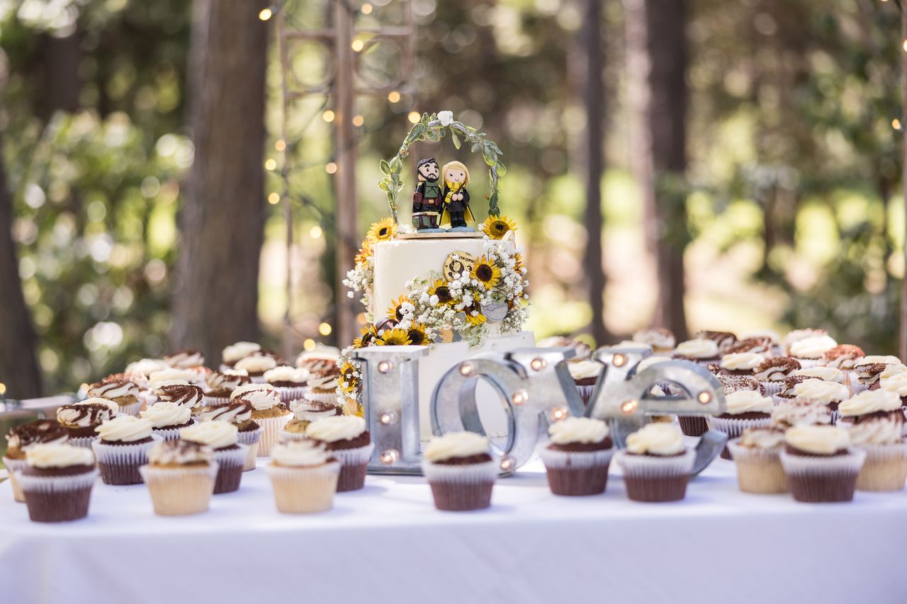 The full dessert table with the wedding cake, the LOVE letters and trays of cupcakes