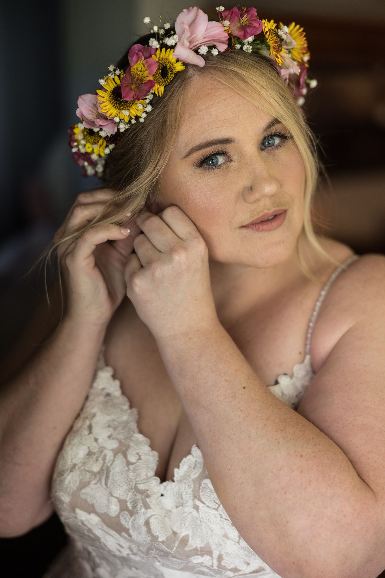 Abney looks into the camera while putting on an earring, wearing her flower crown