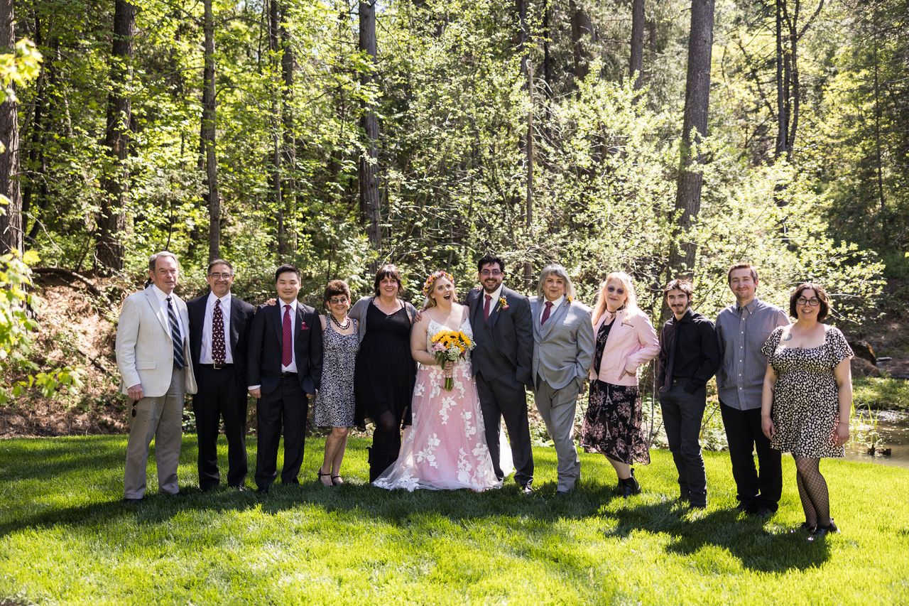 Abney and Chris stand with a row of family members on the lawn in front of the pines