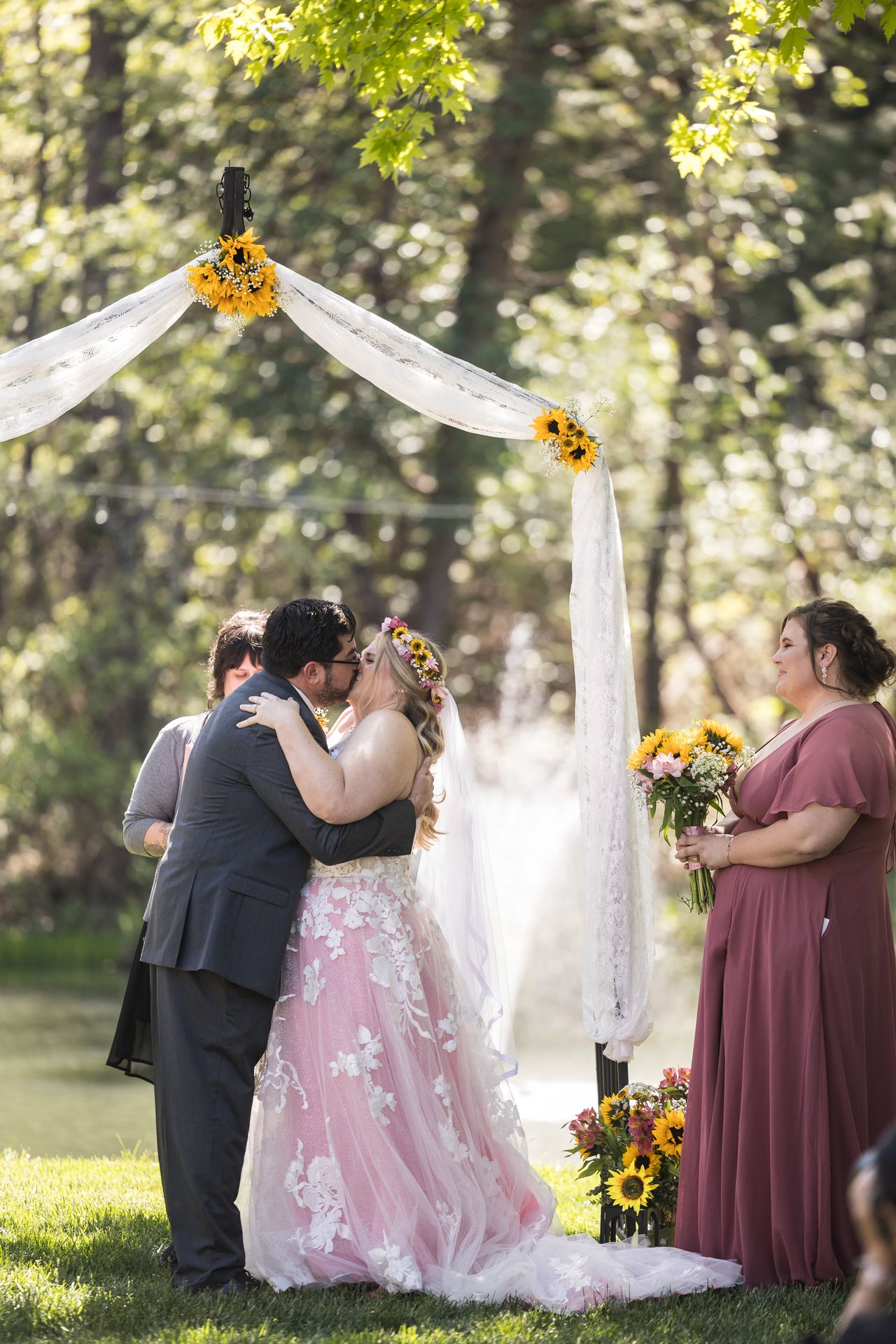 Abney and Chris share their first kiss as a bridesmaid smiles beside them