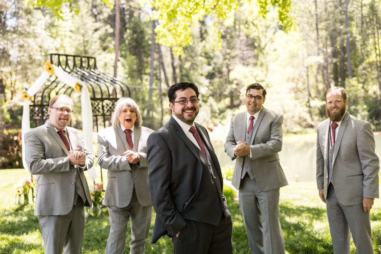 Chris and his wedding party laugh together near the ceremony arbor