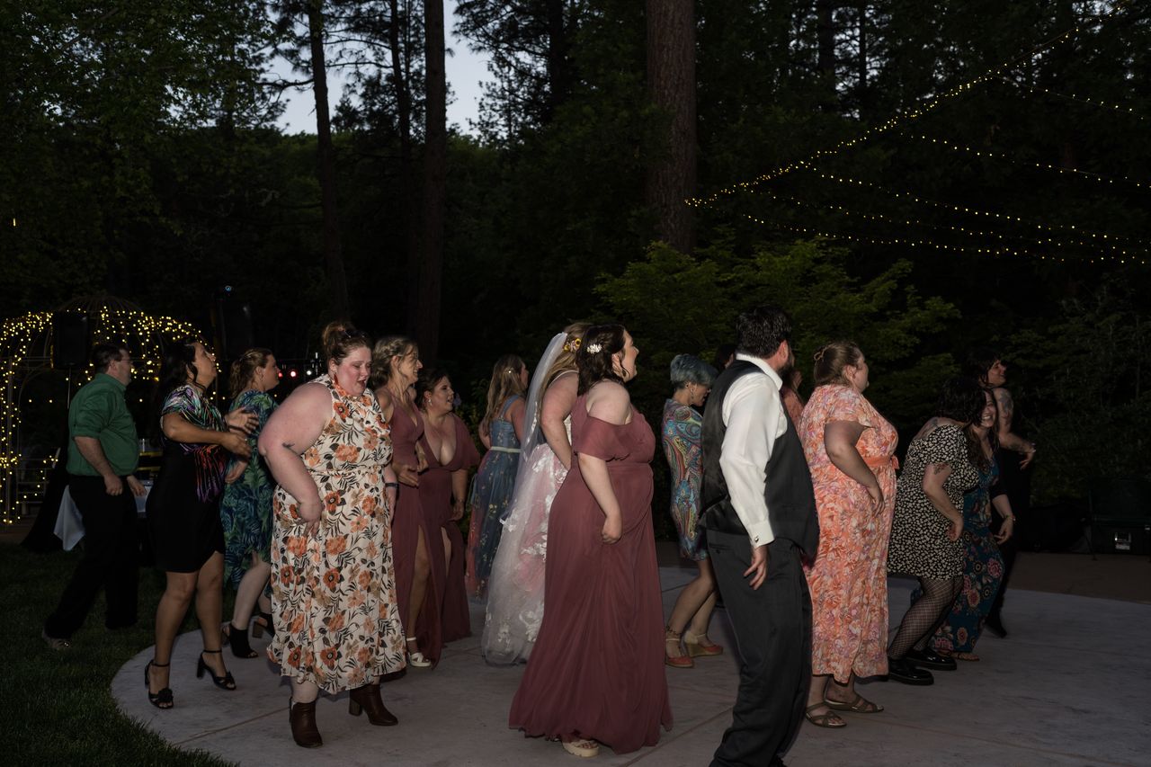 Guests line up for a group dance on the patio as night falls