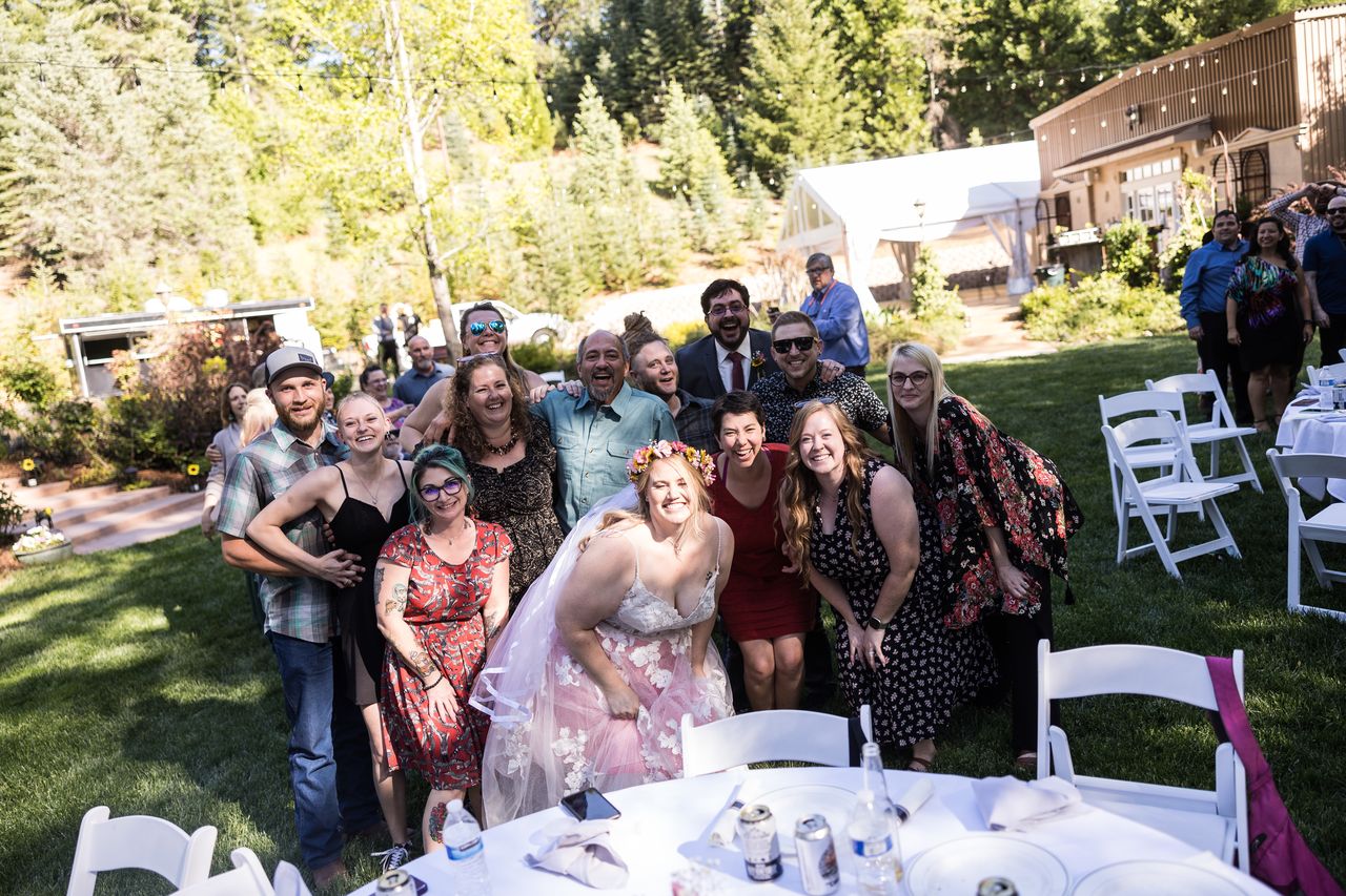 Abney crouches in front of a big group of guests for a photo beside the reception tables