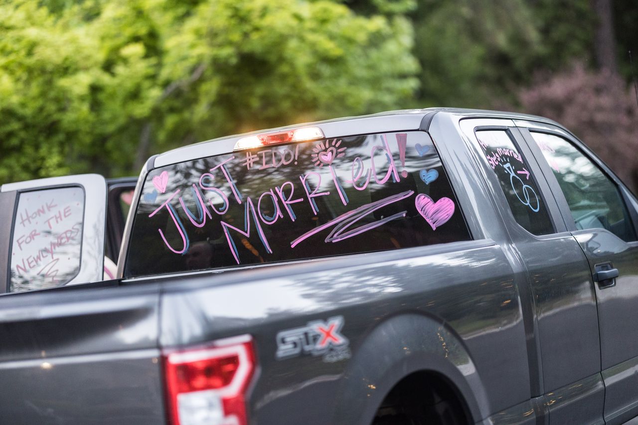 A pickup truck with Just Married written across its back window in pink and purple