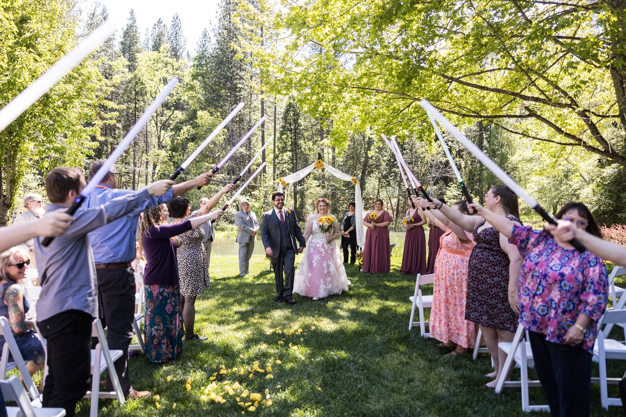 Guests raise lightsabers into an arch as Abney and Chris start back up the aisle