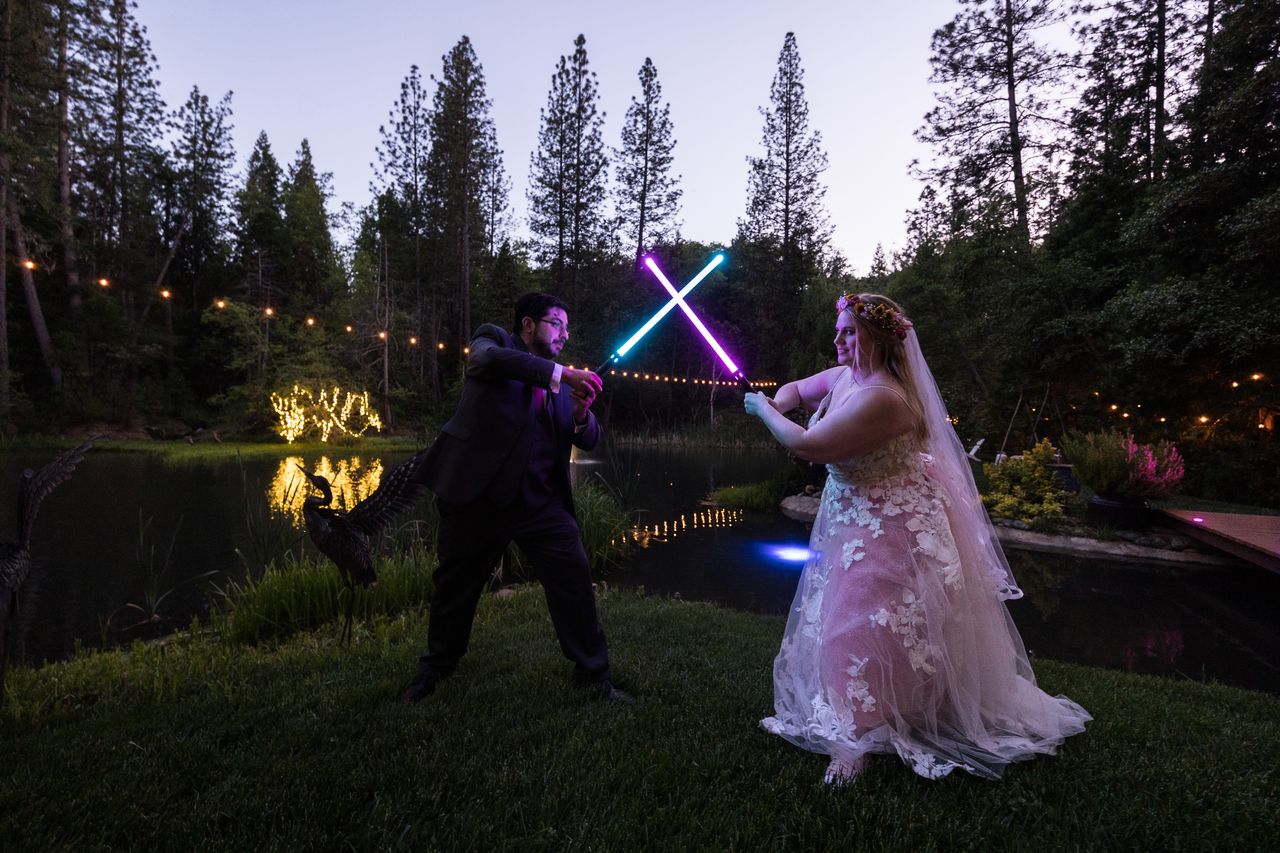 Abney and Chris cross a blue lightsaber and a purple one, their faces lit by the glow