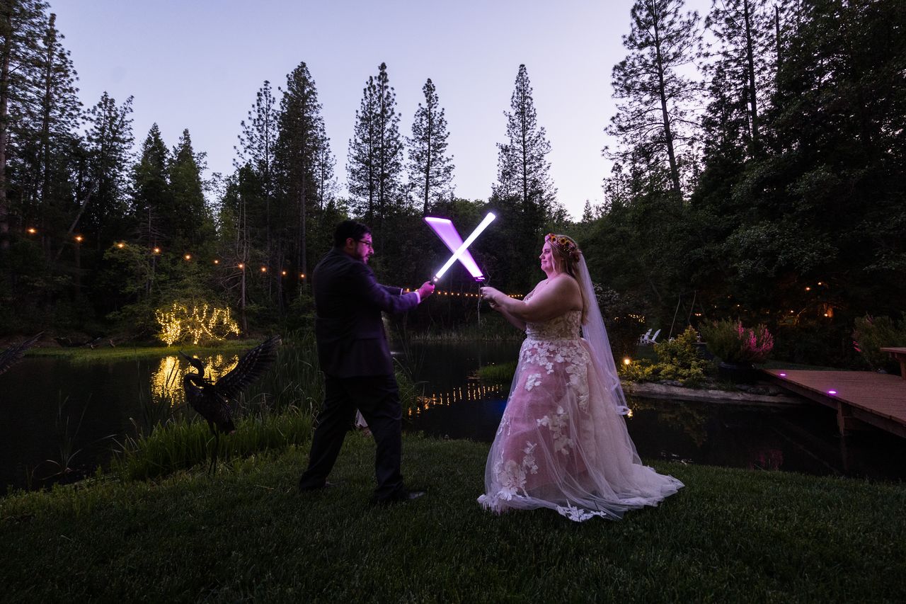 Abney and Chris lock lightsabers on the lawn as dusk settles over the pond