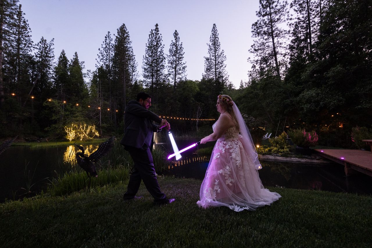 Abney and Chris duel with lightsabers held low, beside the pond at dusk