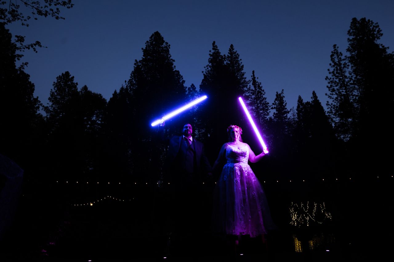 Abney and Chris hold their lightsabers high against the night sky
