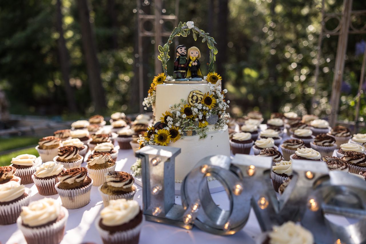 Cupcakes and metal letters spelling LOVE in front of the wedding cake