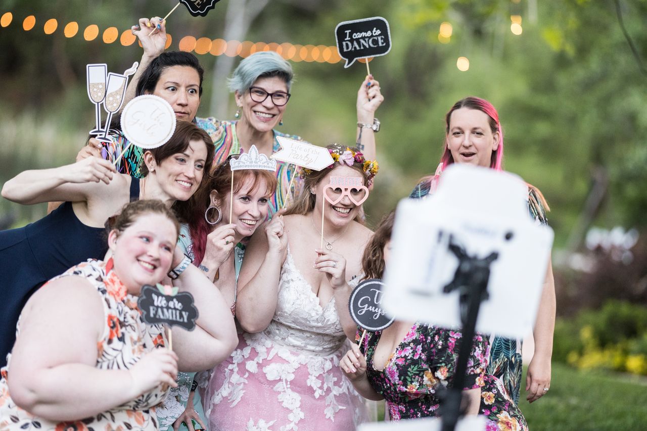 Abney and her guests crowd in front of the photo booth with props, including champagne glasses and an I came to dance sign