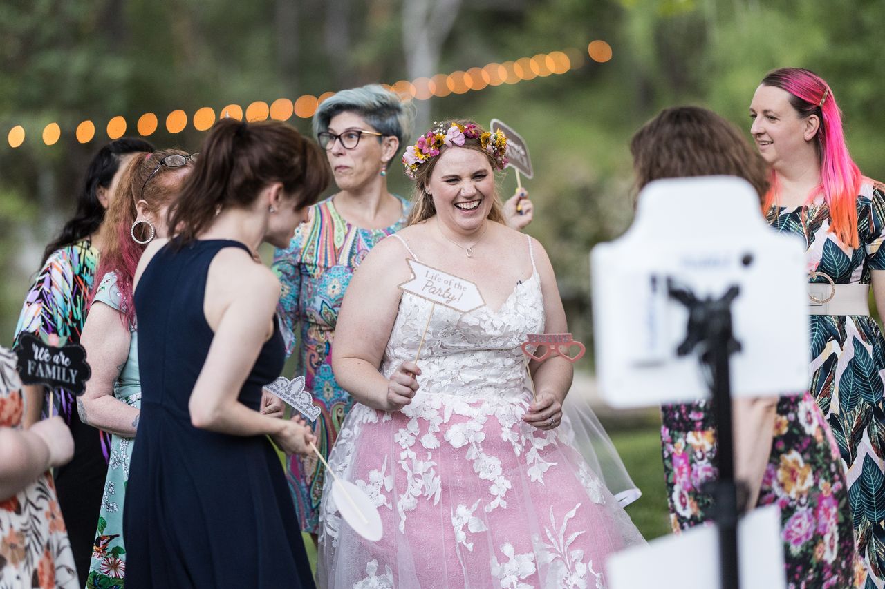 Abney laughs with a Life of the Party prop in her hand as guests gather at the photo booth