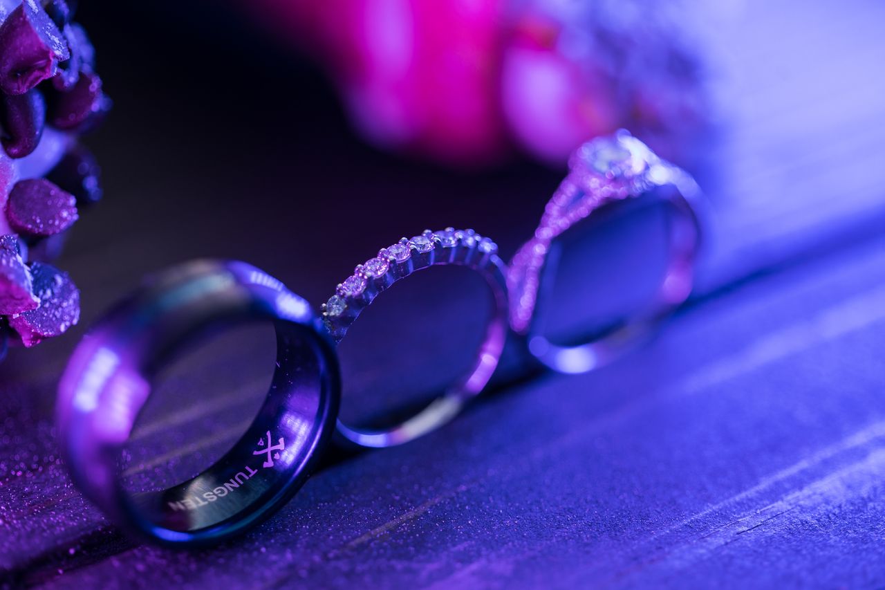 The three wedding rings lined up on a wooden board in purple light