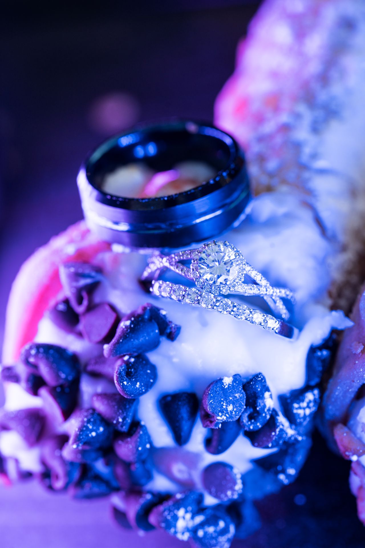 A close view of the engagement ring and wedding bands on a cannoli dipped in chocolate chips