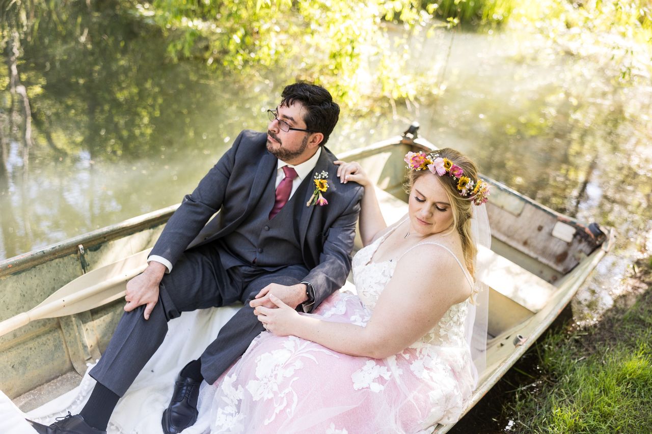 Chris looks at Abney as they sit in a rowboat with sunlight streaming through the trees