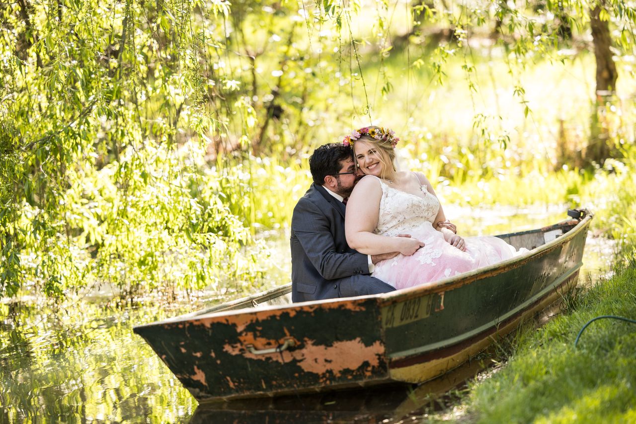 Abney and Chris sit close in an old rowboat among the willows by the pond