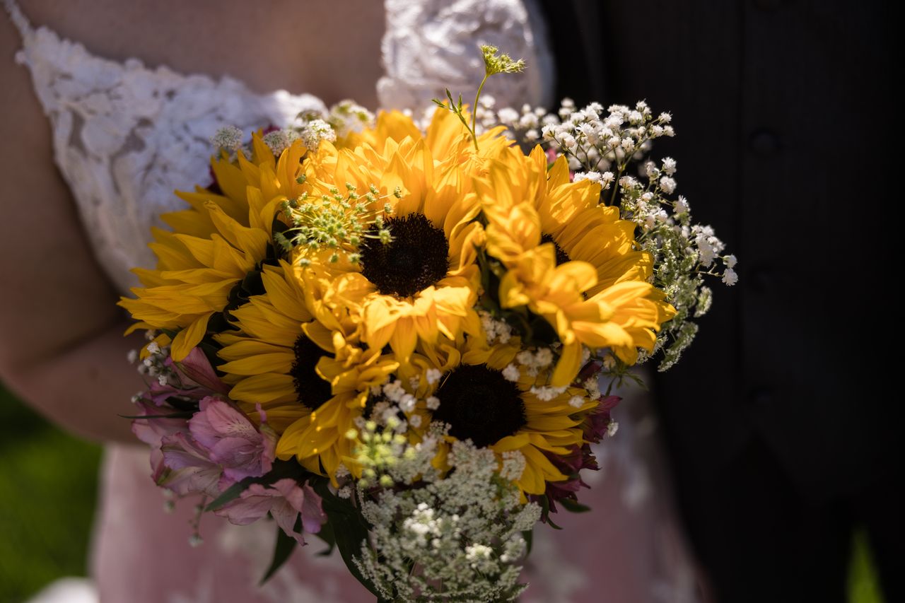Abney's bouquet of sunflowers, pink blooms and baby's breath held against her lace gown