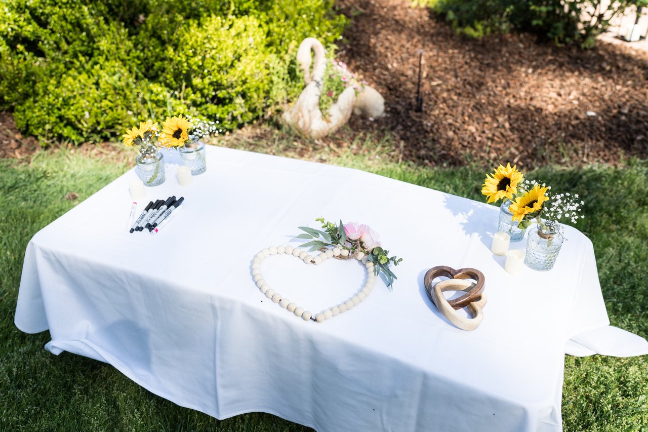 The sweetheart table set with sunflowers and a heart wreath on the lawn