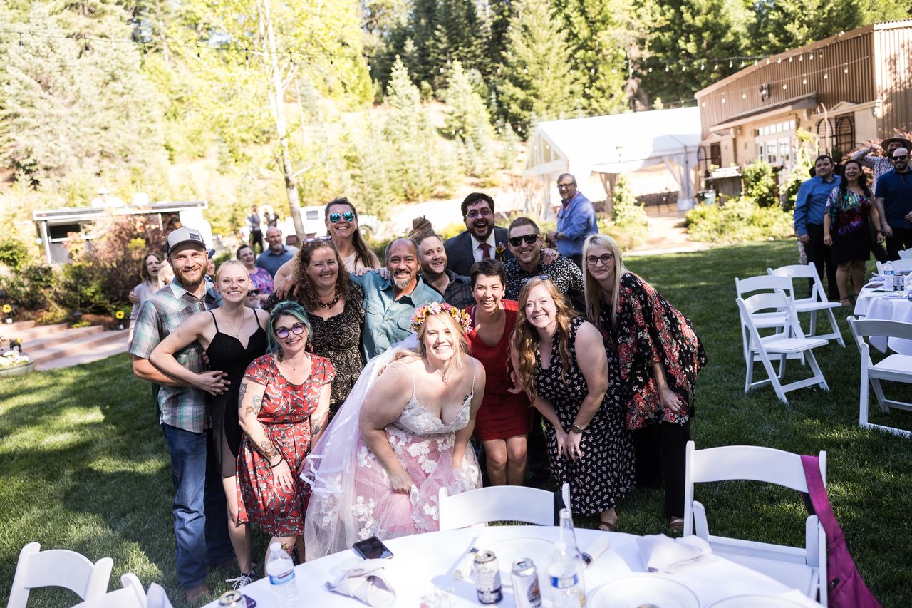 A big group of guests gathers behind their table for a photo with Abney