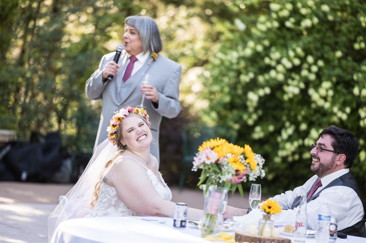 Abney and Chris laugh as a family member gives a toast behind them