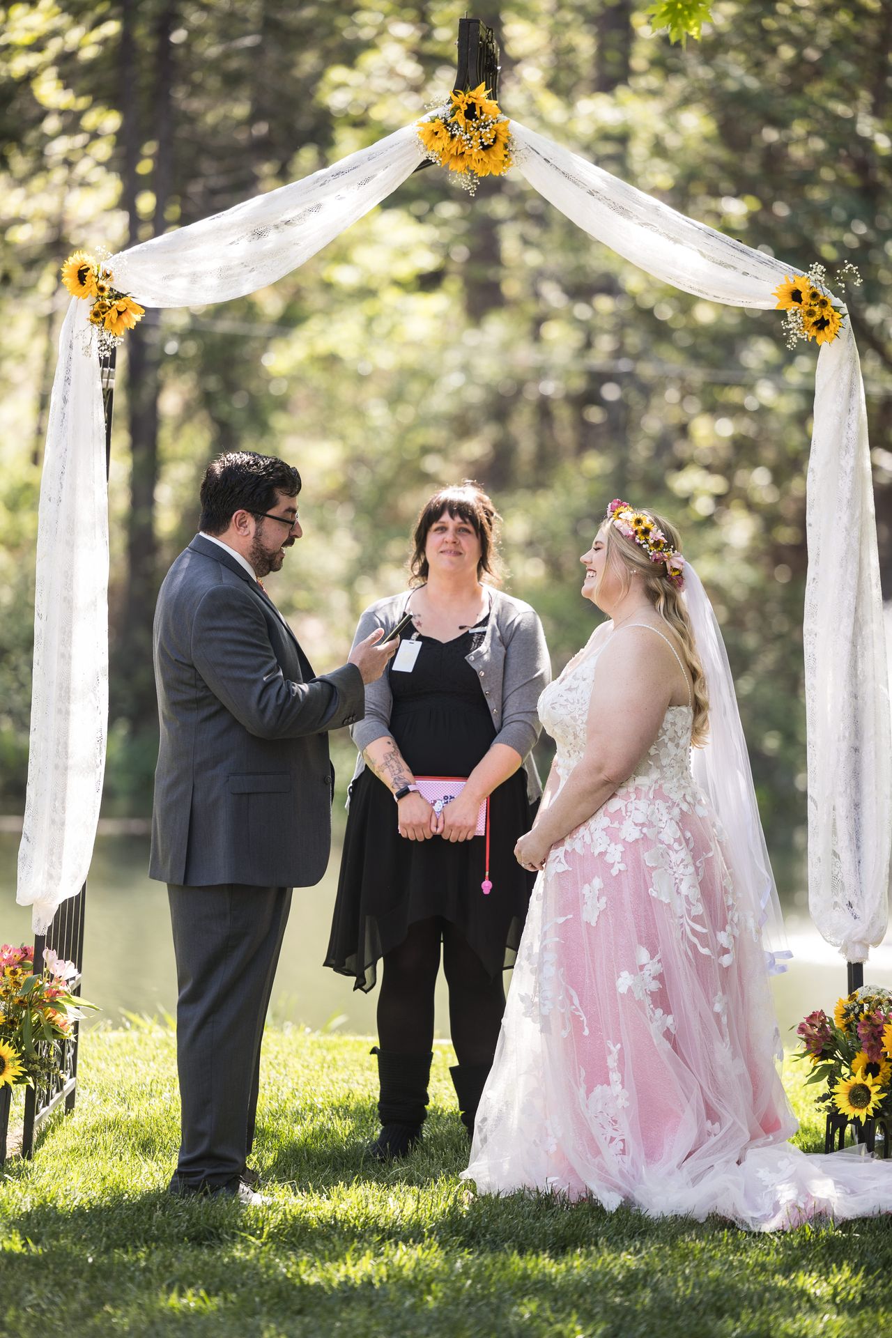 Abney and Chris face each other under the sunflower arbor as the officiant looks on