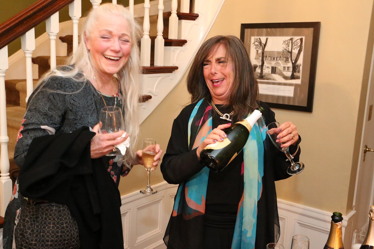 Two guests laugh as champagne is poured by the staircase