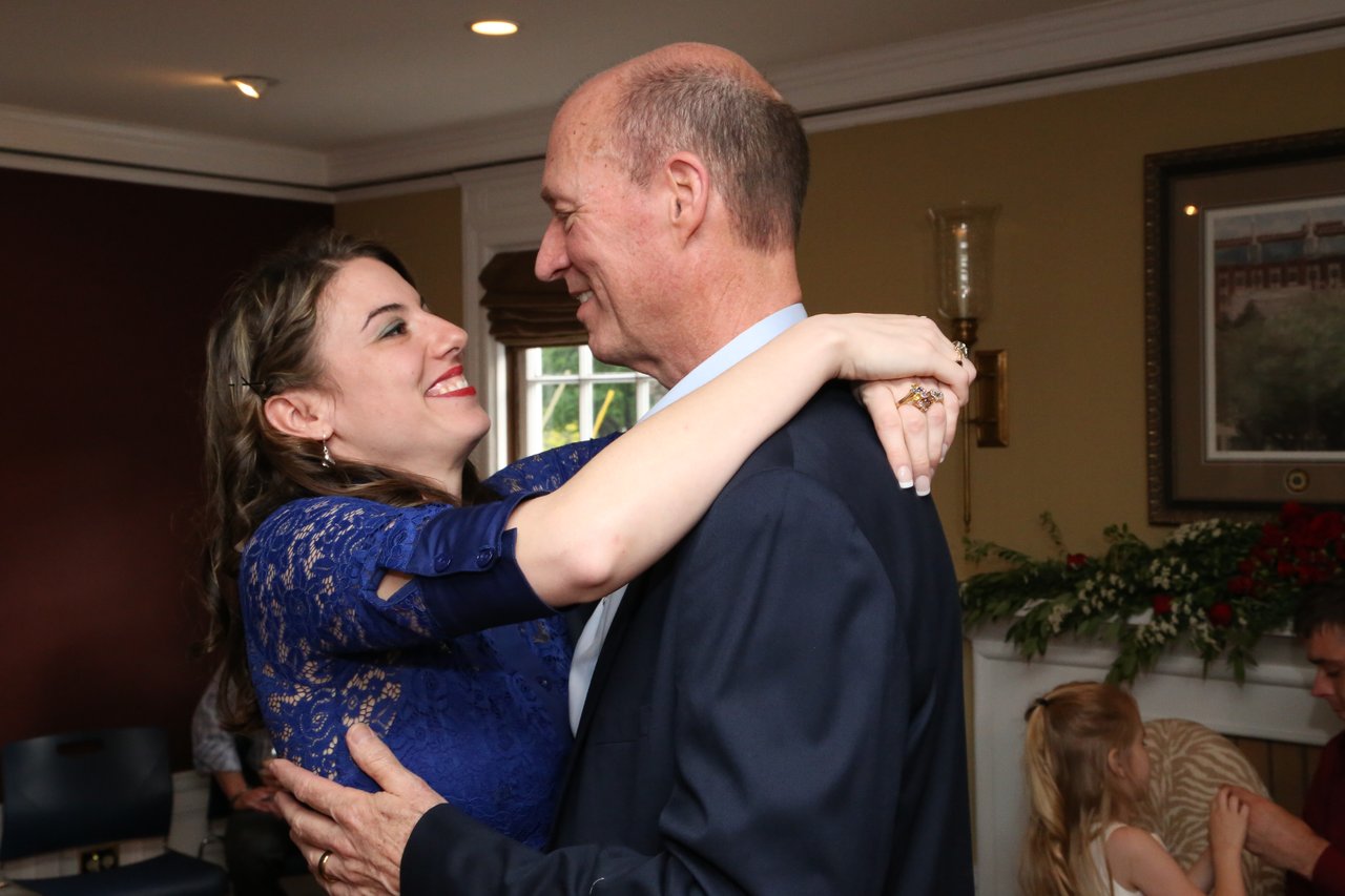 Tim laughs as a young woman in blue lace hugs him on the dance floor