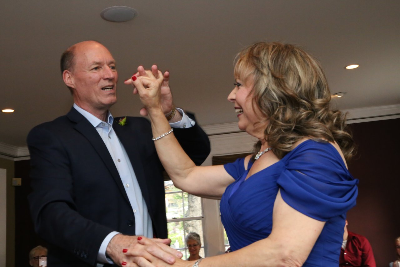 Alexanne and Tim laugh as they dance with their hands raised