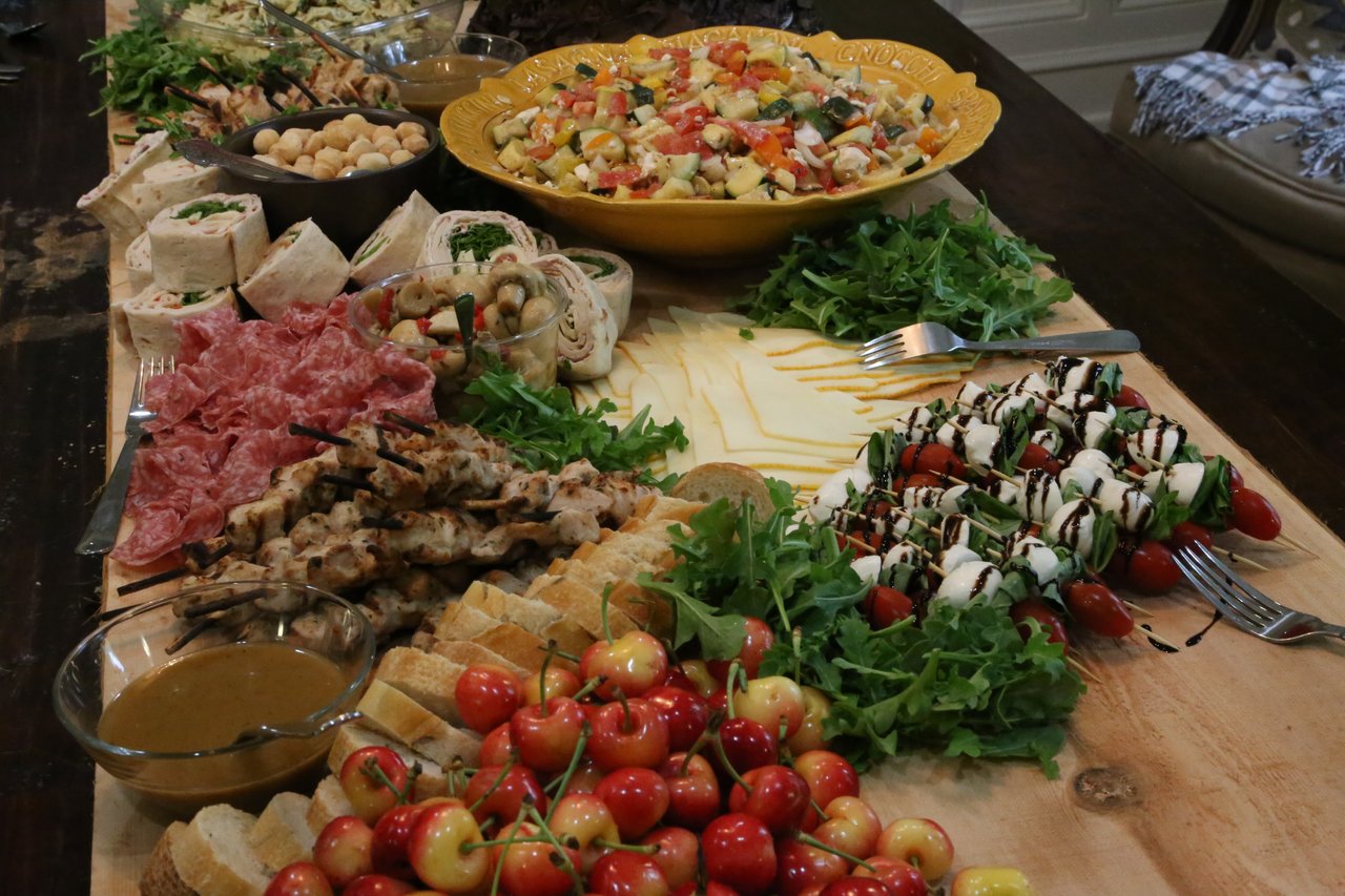 A long grazing table of salads, cheeses, cured meats and cherries