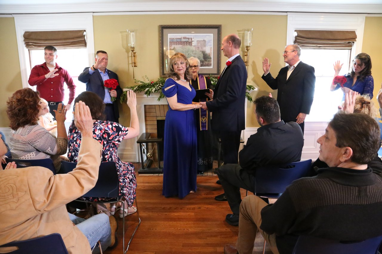 Guests raise their hands toward Alexanne and Tim during the ceremony