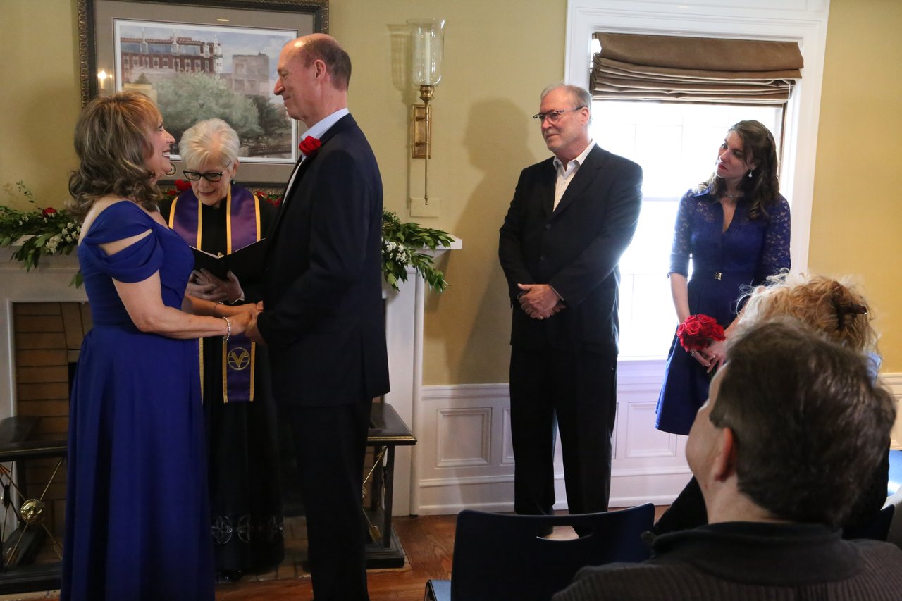 Alexanne and Tim hold hands in front of the officiant at the fireplace