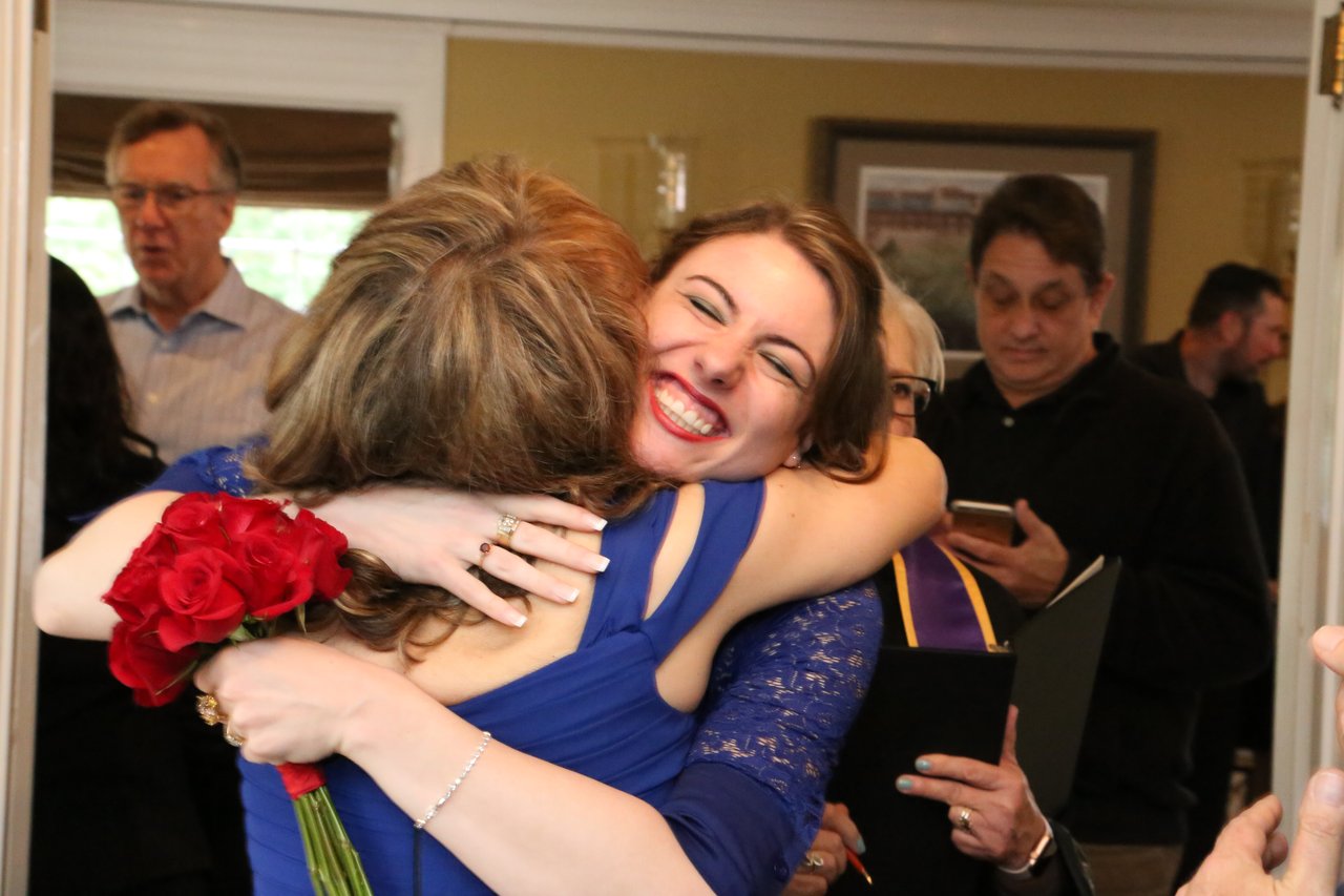 Alexanne hugs a beaming young woman in blue lace after the ceremony