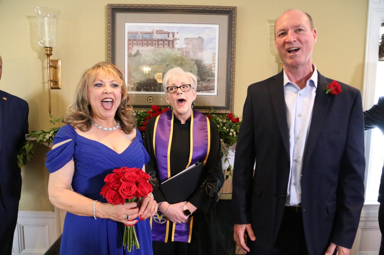 Alexanne cheers with her roses as Tim and the officiant laugh