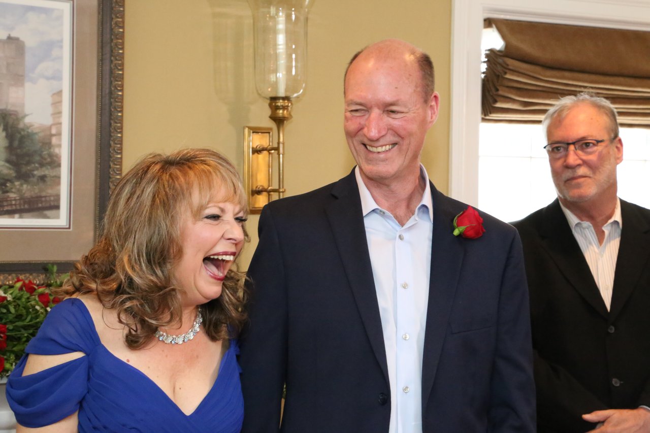 Alexanne bursts out laughing beside a grinning Tim during the ceremony