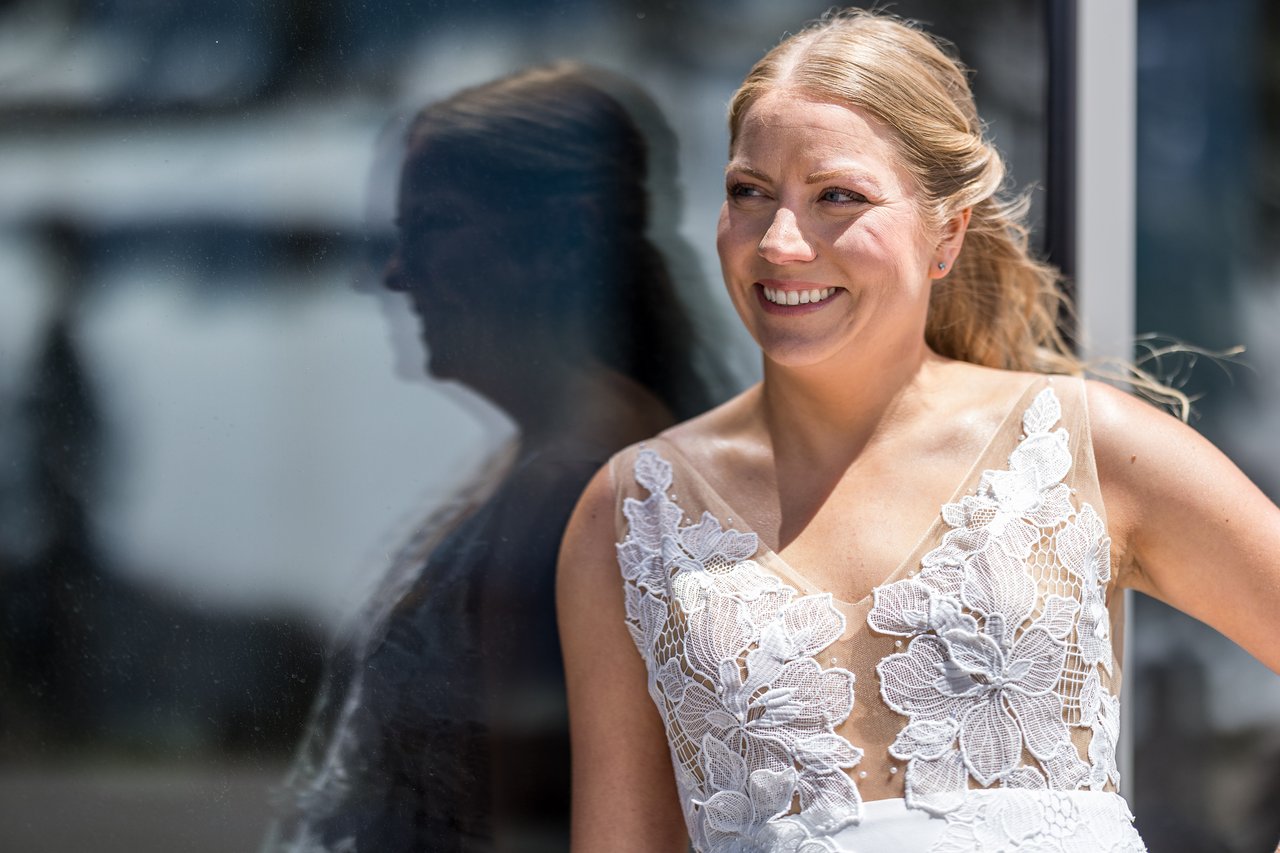 Ali laughs beside her reflection in the glass