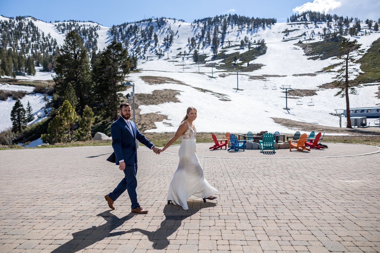 Ali and Robert walk across the plaza with Mt Rose's snowy slopes behind them